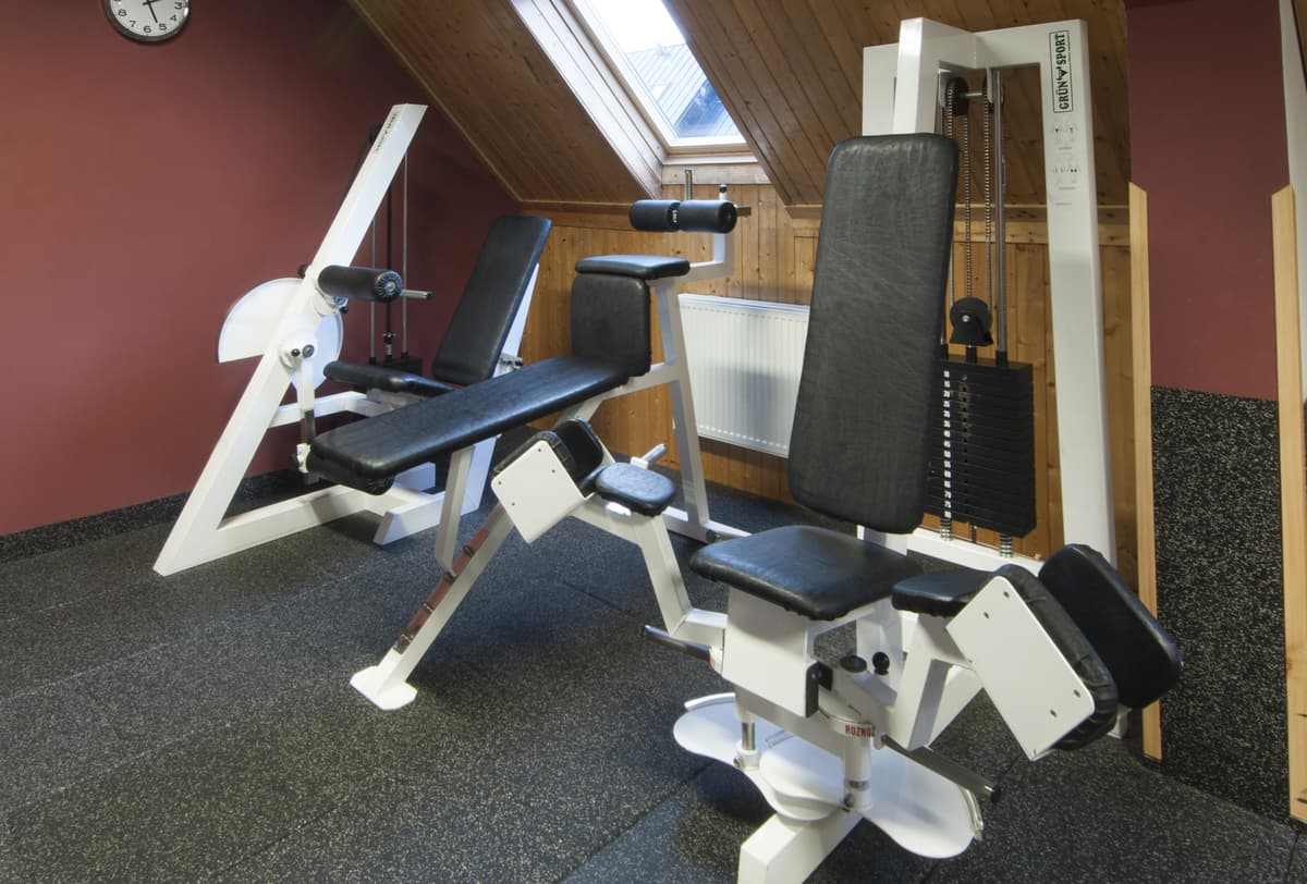 Fitnessraum mit einer Bank für Übungen und Gewichten mit einer roten Wand.