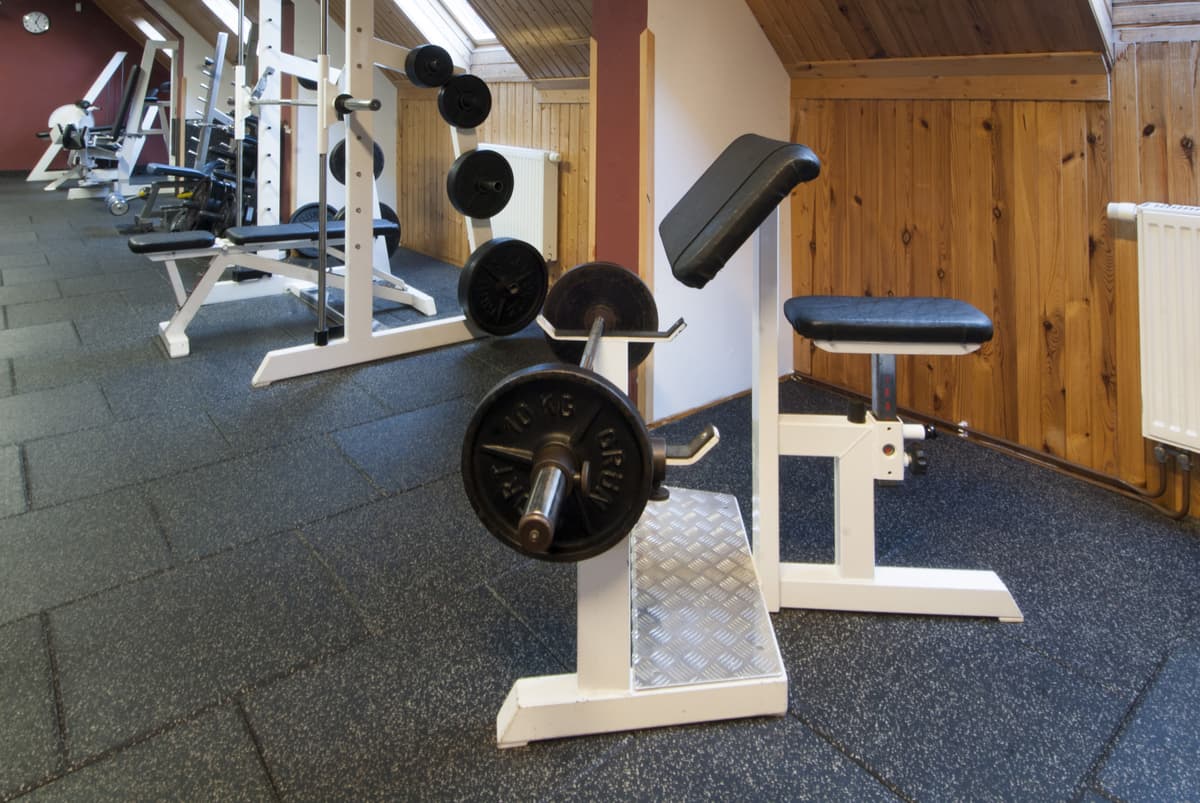 Part of the gym with a weight bench and dumbbells on the floor.