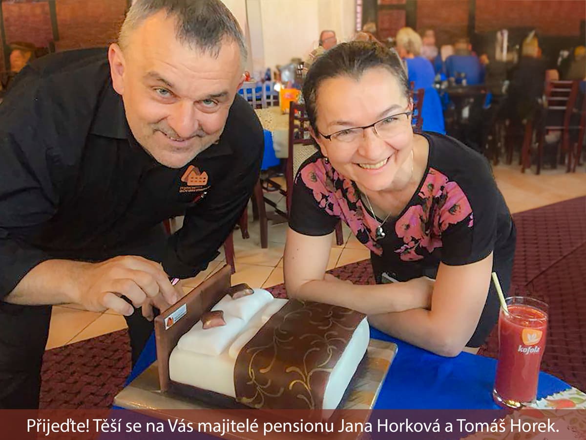 Dva usměvaví lidé u dortu v restauraci