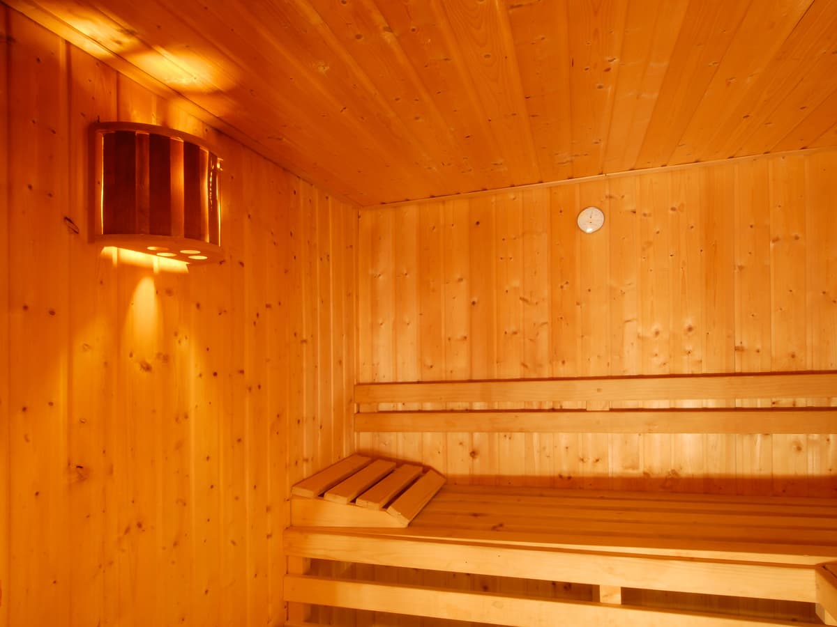 Das Interieur einer traditionellen Holzsauna mit Bänken und Beleuchtung.