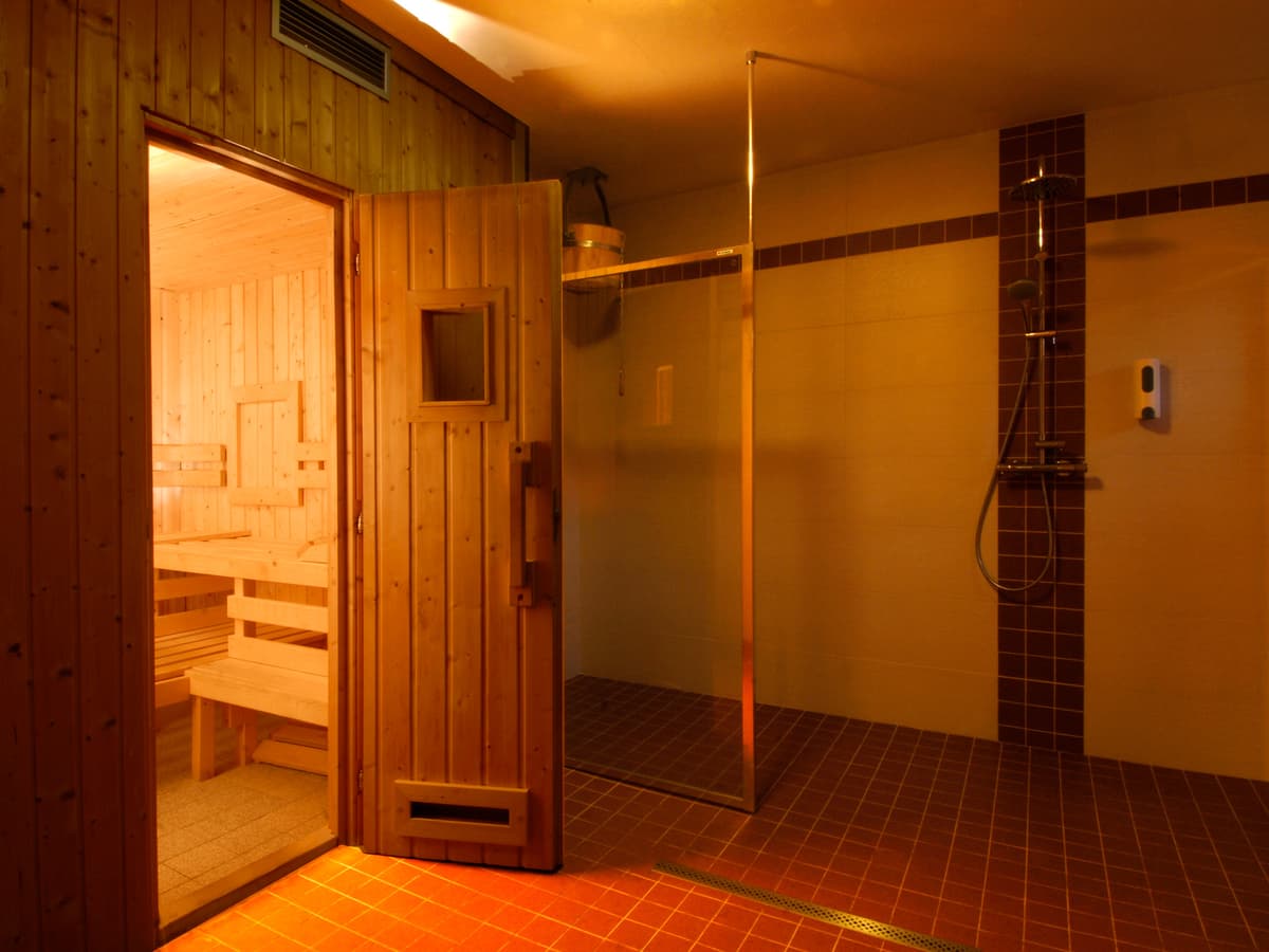 Eingang zur Sauna und Duschkabine im Entspannungsbereich mit Fliesen und Holzelementen.