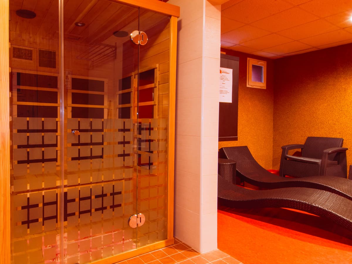 Eine Infrarotsauna mit Glastüren und Infrarotpaneelen an den Wänden.